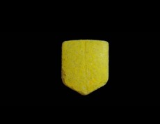 Das Bild zeigt eine gelbe Pille in UPS-Logo Form mit Bruchrille
